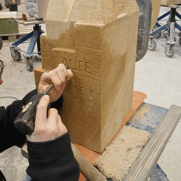 Azubi meißelt auf Stein